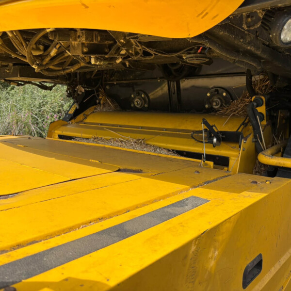 Underbelly of a yellow machine showing exposed hoses, wiring, and mechanical components just beneath the body.