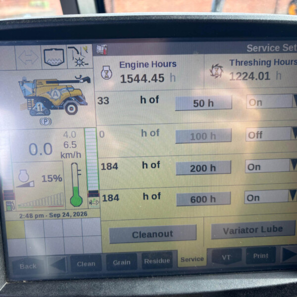 Close-up of an agricultural machine display showing engine hours 1544.45 h and threshing hours 1224.01 h with control panels and a combine graphic on the left.