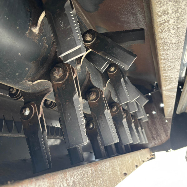Close-up of interlocking serrated metal blades and bolts inside an industrial machine.