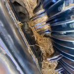Close-up of a farming machine interior with metal blades and straw scattered around, likely part of a baler or combine.