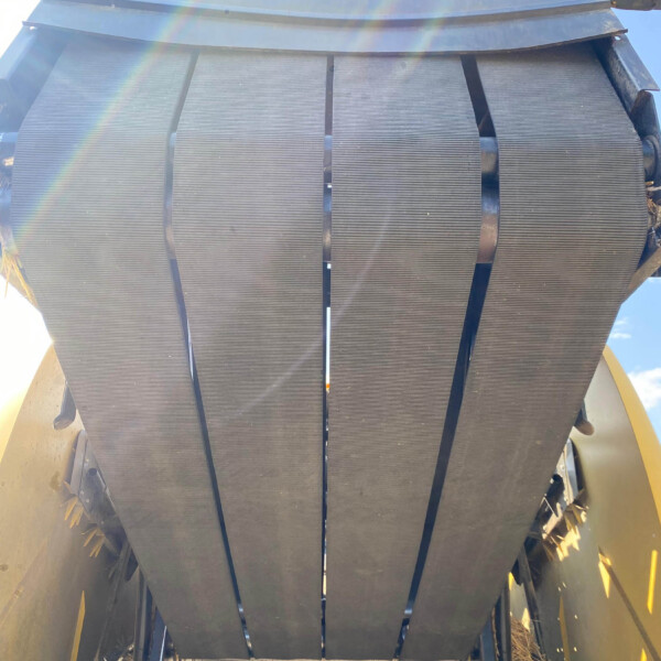 Close-up of a large industrial belt conveyor with parallel black rubber belts and metal supports seen from below