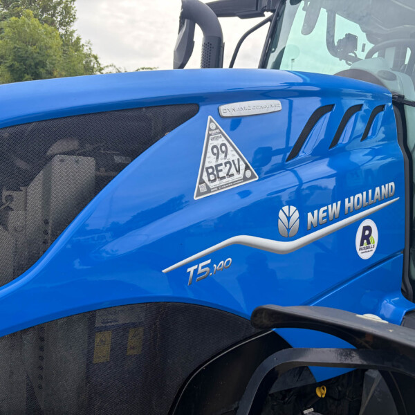 Close-up of a blue New Holland tractor cabin with 'Dynamic Command' badge and model label T5.140 on the hood.