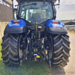 Rear view of a blue tractor with oversized rear tires, license plate FY70 CFM, and visible hitch hydraulics at the back.