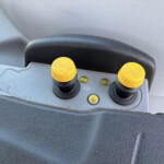 Close-up of two yellow circular knobs on a gray vehicle dashboard control panel.