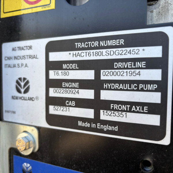 Close-up of a tractor identification plate with the label 'TRACTOR NUMBER' and serial/model numbers, including 'Made in England' text on a dark metal surface.