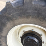 Close-up of a large off-road tractor tire showing deep treads and a white rim with bolts.