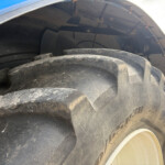 Close-up of a dirty, heavy-duty tire tread on a large truck wheel seen at ground level