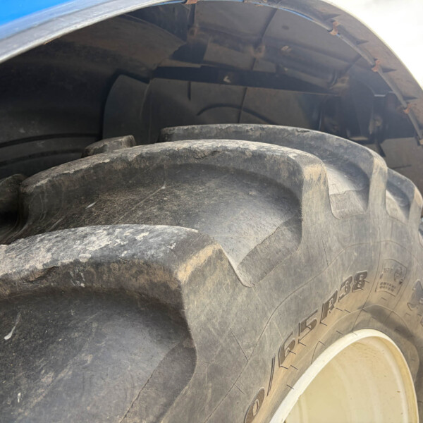 Close-up of a dirty, heavy-duty tire tread on a large truck wheel seen at ground level