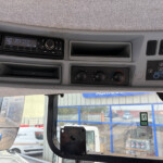 Vehicle cockpit dashboard with a radio unit, storage slot, and climate control knobs visible on the panel behind the windshield