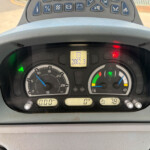 Close-up of a tractor dashboard with analog gauges, a central digital hour meter reading 2082.3, and various warning lights above the steering wheel.