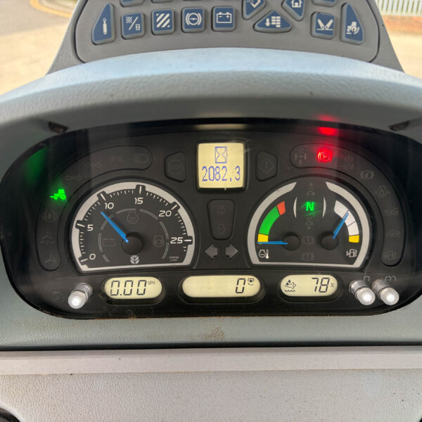 Close-up of a tractor dashboard with analog gauges, a central digital hour meter reading 2082.3, and various warning lights above the steering wheel.
