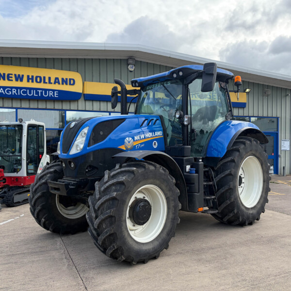 Blue New Holland tractor parked outside an agricultural dealership with the building sign in view.