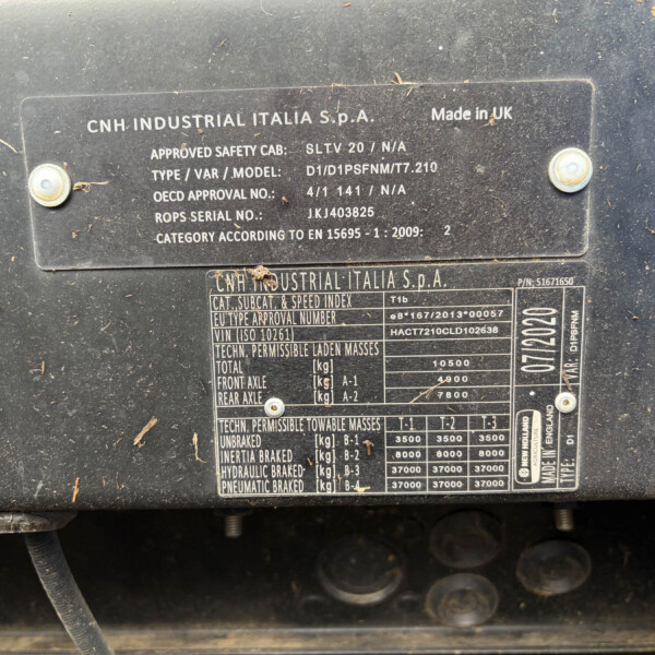 Close-up of a dusty metal data plate on heavy equipment showing CNH INDUSTRIAL ITALIA S.p.A. and model/serial details for identification, including 'Made in UK'.