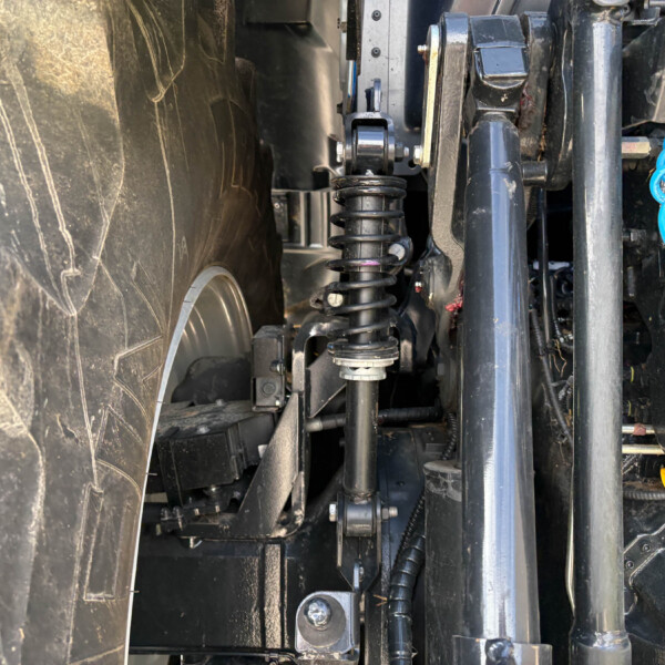 Close-up of a heavy-duty vehicle suspension with a coil spring and shock absorber among black chassis components.