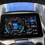 Digital motorcycle dashboard display showing RPM around 850, with bluepower branding and surrounding gauges.