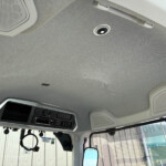 Interior of a vehicle cab ceiling with an overhead console and speakers visible in the headliner on the right side.