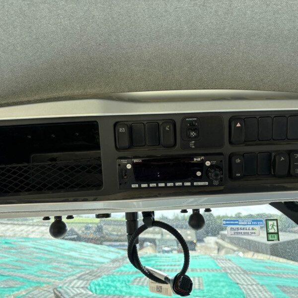 Overhead vehicle dashboard with a row of black switches and a central display screen in a truck cab.