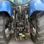 Rear view of a blue tractor showing the hydraulic hitch, control valves, and hoses between oversized rear tires
