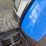 Close-up of a dirty truck step and tire tread next to a blue vehicle body, showing dust and wear.