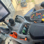 Interior of a tractor cab showing a joystick, colorful control panel, and a large touchscreen display for guidance and controls