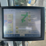Close-up of a rugged monitor showing a Swath Map with green field paths and run/status panels inside a vehicle cab.
