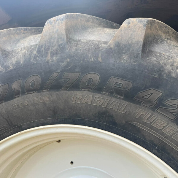 Close-up of a dusty heavy-duty tire with embossed lettering and a white wheel rim visible at the bottom
