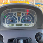View of a vehicle dashboard with a speedometer showing 0.0 mph and the center display reading 5151.8, set against a construction-site background outside the windshield.