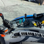 Close-up of a heavy vehicle dashboard with multiple colored levers and a coiled gear shift, viewed from the driver’s seat