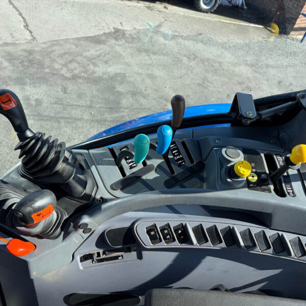 Close-up of a heavy vehicle dashboard with multiple colored levers and a coiled gear shift, viewed from the driver’s seat