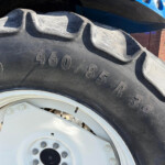 Close-up of a large tractor tire with deep treads and a white wheel hub, part of agricultural equipment.