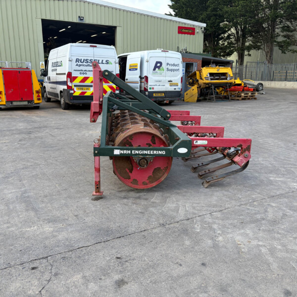 Industrial yard scene with two white Russell's vans near a green warehouse; foreground shows a red NRH Engineering roller/compactor piece of equipment.