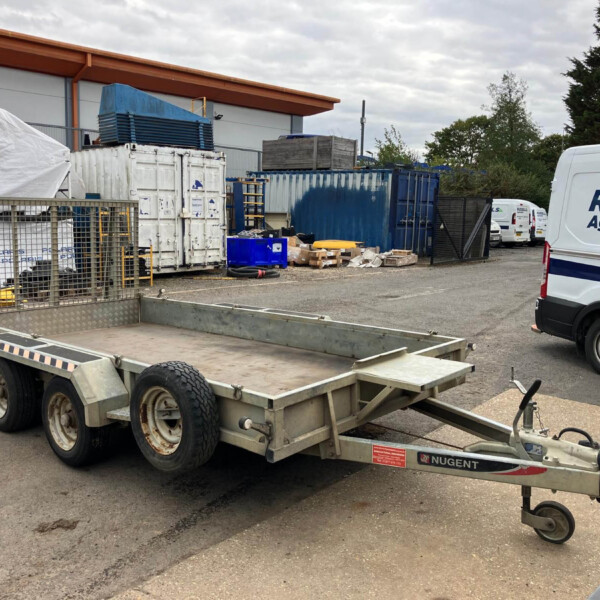 Industrial yard with a metal trailer, blue containers, and a white delivery van reading 'RUSSELL Agriculture' in the background.