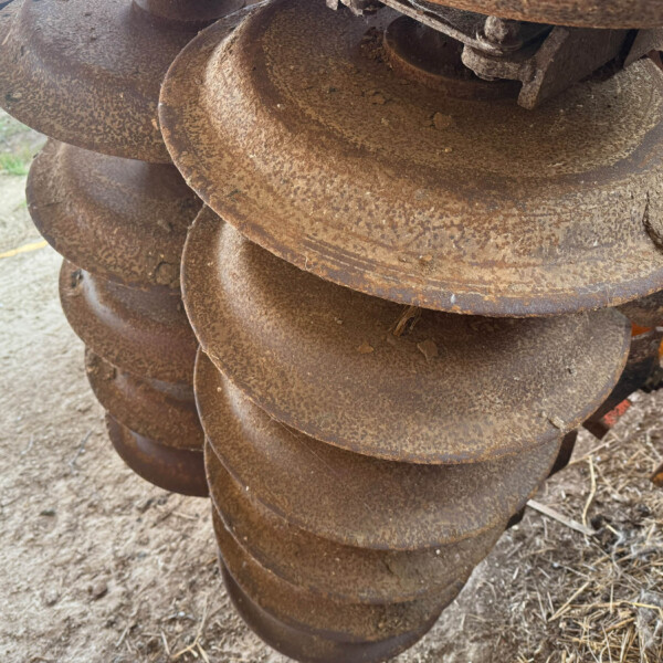 Stack of large rusted auger drill bits, stacked in a spiral outdoors