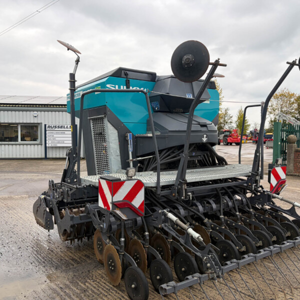 Large blue farming implement with rotating disk harrows on a trailer in a workshop yard, secured for transport from Russells.