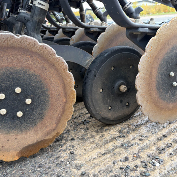 Close-up of rusted scalloped disc blades on agricultural tillage equipment set on gravel ground