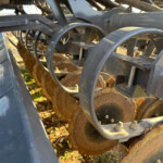 Close-up of a metal frame and hoses on heavy machinery, showing rust and dirt.