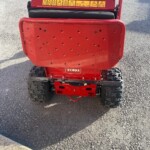 Back view of a red Toro walk-behind lawn aerator/dethatcher with a perforated rear guard and rugged tires, warning labels visible.