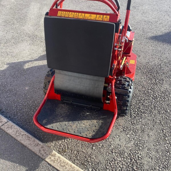 Red plate compactor on paved surface with a black protective cover and sturdy handles, used to compact asphalt or soil.