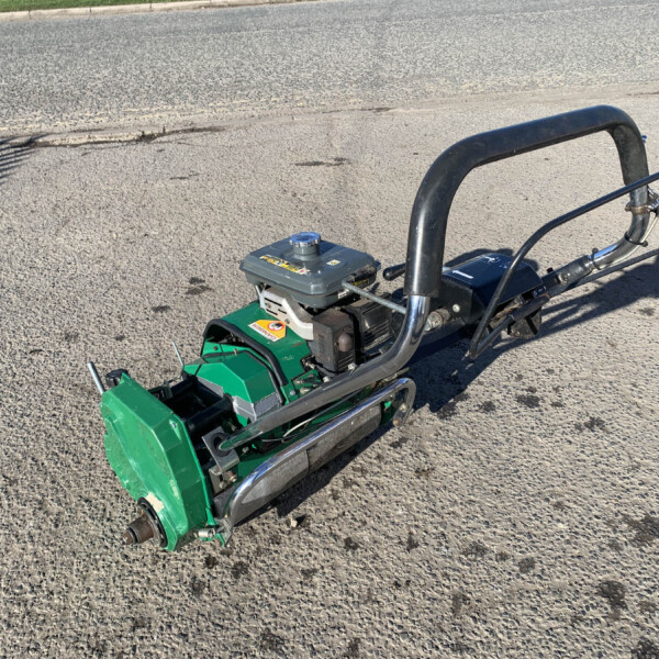 Gas-powered plate compactor with curved black handle on an asphalt surface, ready for paving work.