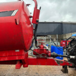 Close-up of red industrial equipment with hoses and hydraulic connectors in an outdoor maintenance yard