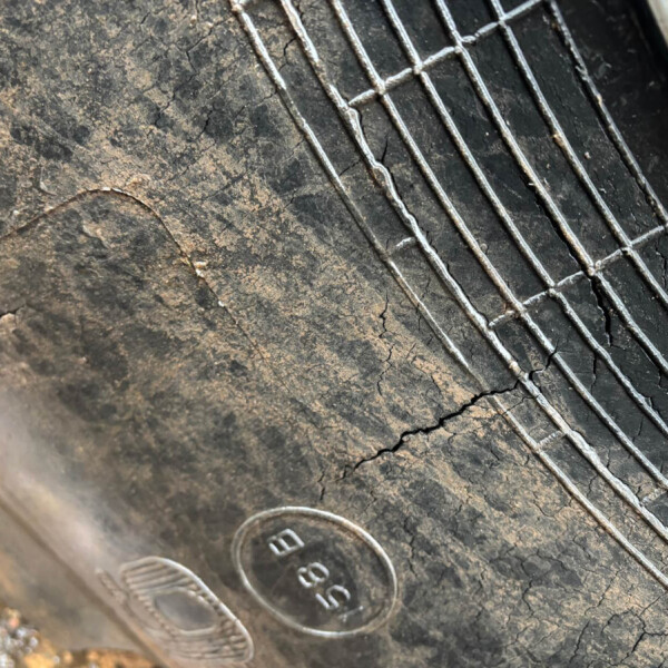 Close-up of a dirty, blackened grill grate with parallel metal bars and rust along the edges