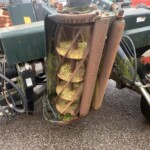 Close-up of a rusted spiral auger inside weathered green industrial equipment, with moss growing on the surfaces.