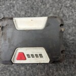 Close-up of a dirty rectangular electrical switch with a red emergency stop button and a metal label plate on the black housing.