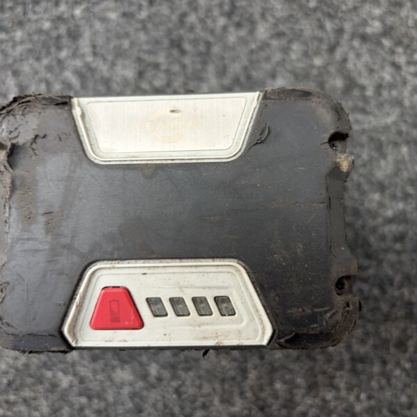 Close-up of a dirty rectangular electrical switch with a red emergency stop button and a metal label plate on the black housing.