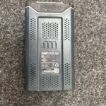 Rechargeable 82V lithium battery with label showing 6 Ah rating and model information on a dark gray casing viewed from the top edge of a worn device.