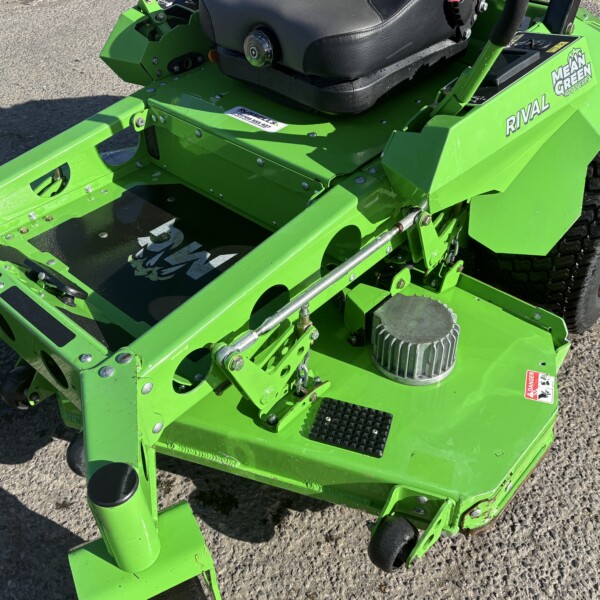 Bright green riding lawn mower frame with black seat, large rear tire, and metal bolts visible on pavement.