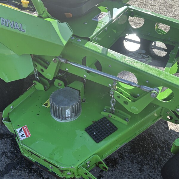 Close-up of a bright green Mean Green Mowers attachment marked 'RIVAL,' showing hydraulic rods and step platforms.