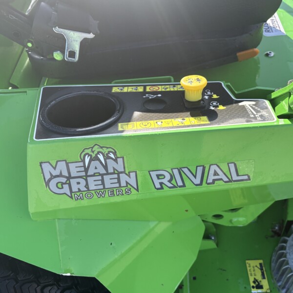 Close-up of a green ride-on mower control deck with a yellow fuel/inspection cap and branding that reads 'Mean Green Rival Mowers' on the side.