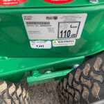 Close-up of a green Billy Goat machine showing model KV601 label and serial number 092624072, with large rugged tires and a metal step.
