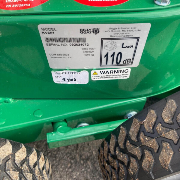 Close-up of a green Billy Goat machine showing model KV601 label and serial number 092624072, with large rugged tires and a metal step.
